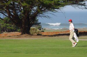 golfer walks along MPCC course with Pacific Ocean in background